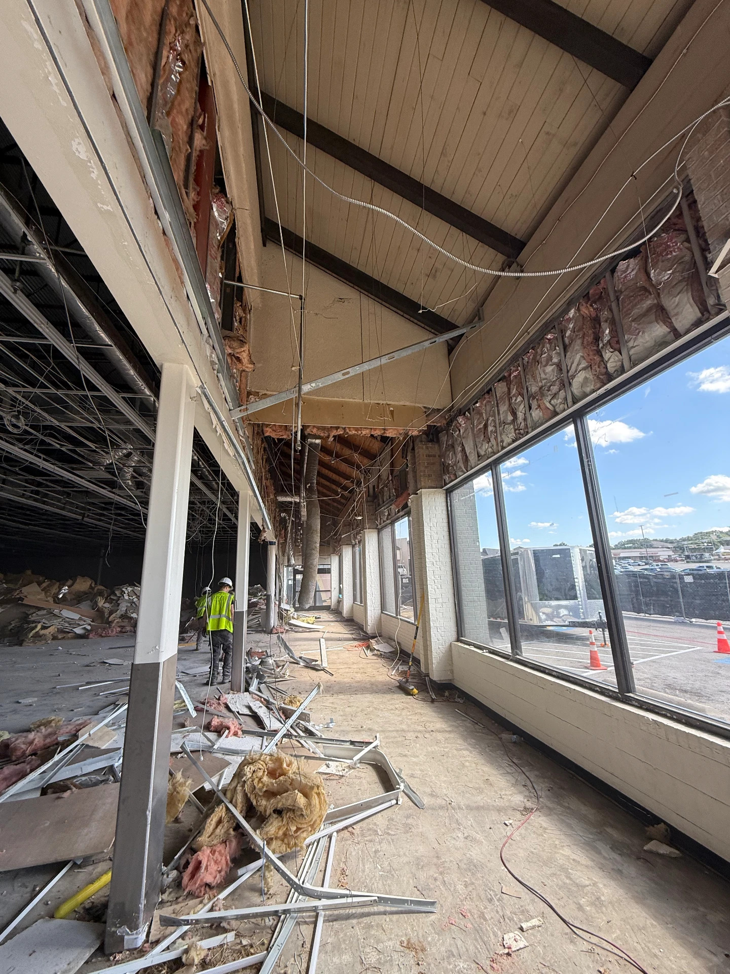 Interior strip-out of a commercial corridor with exposed studs and debris