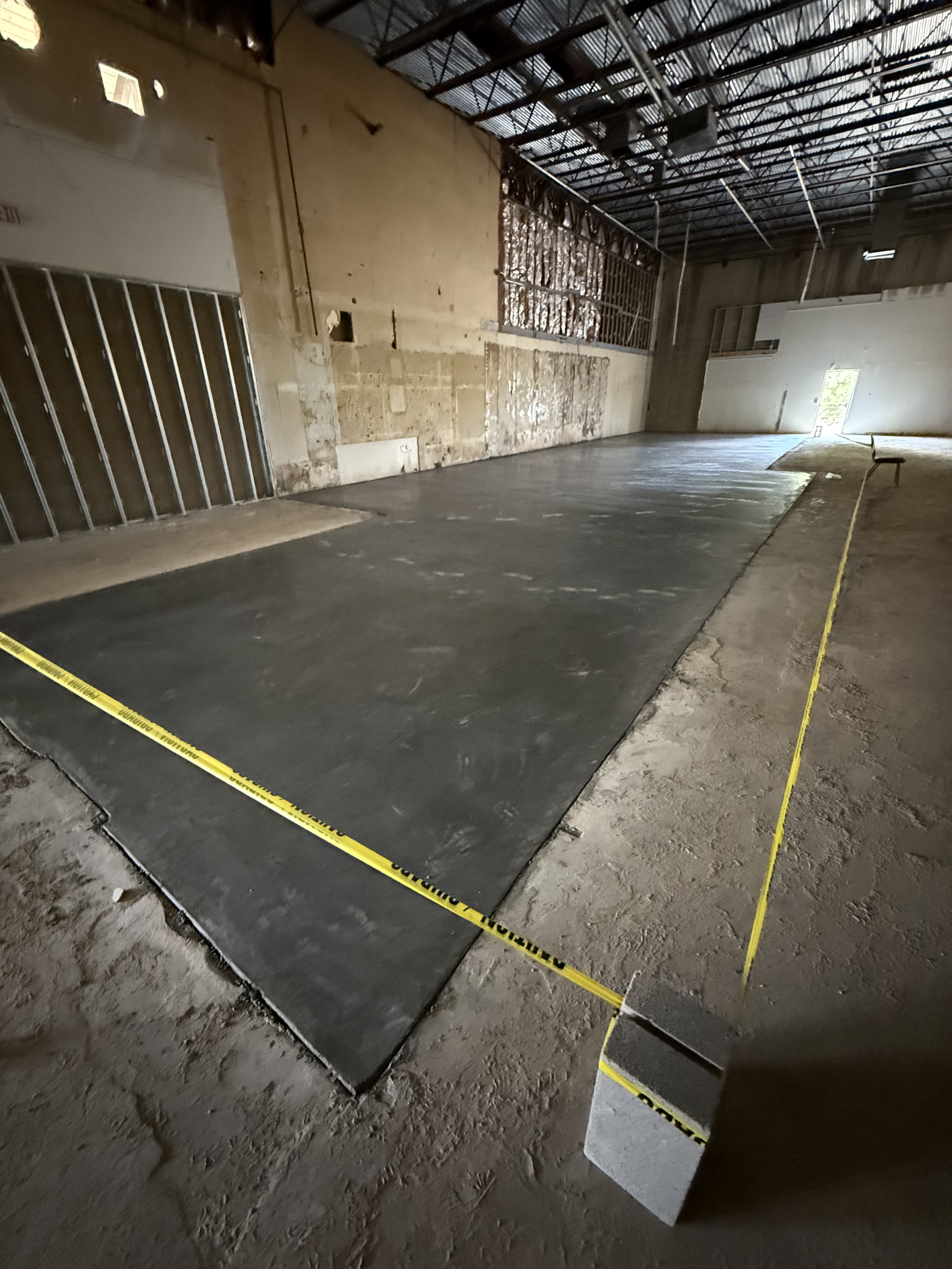 Freshly poured commercial concrete floor with caution tape